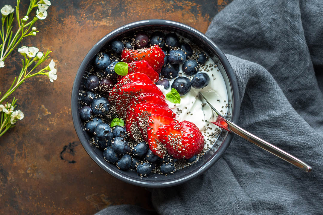 Picture of youghurt and berriesson a table. Good for gut health