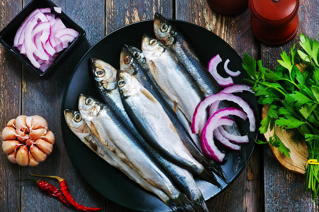 Picture of fish on a plate with vegetables surrounding it