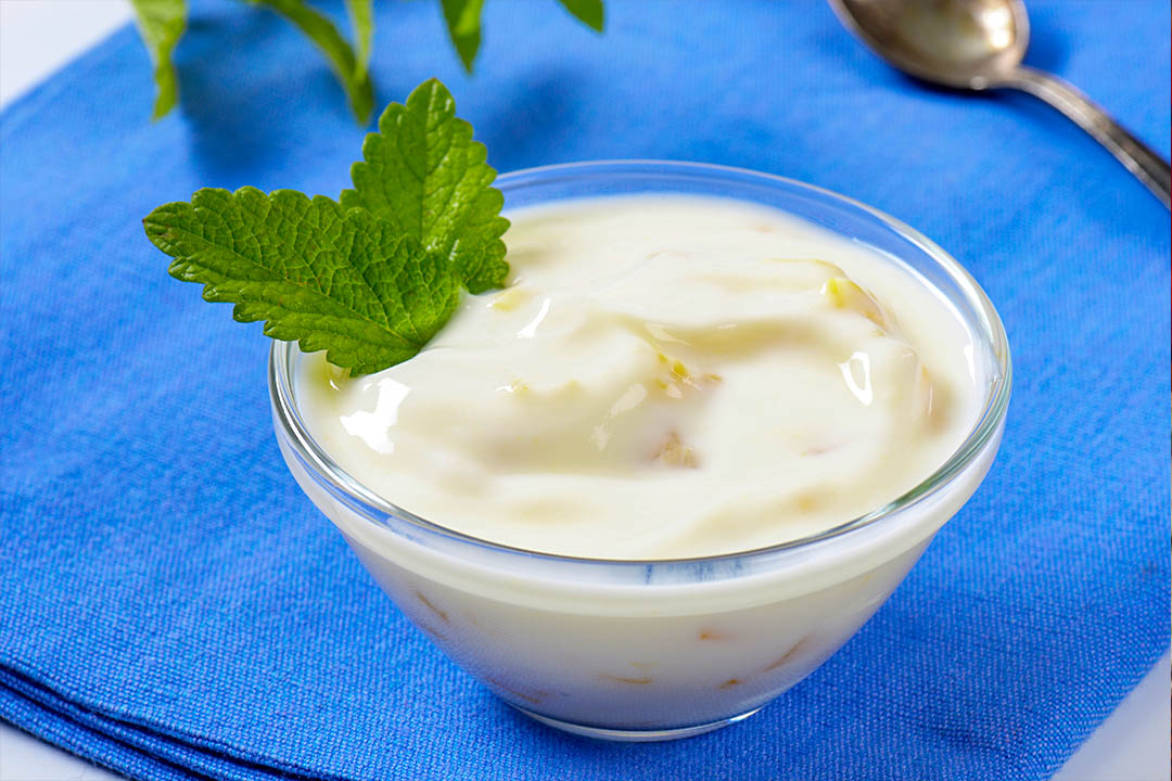 Picture of Yoghurt in a glass bowl with mint leaf.